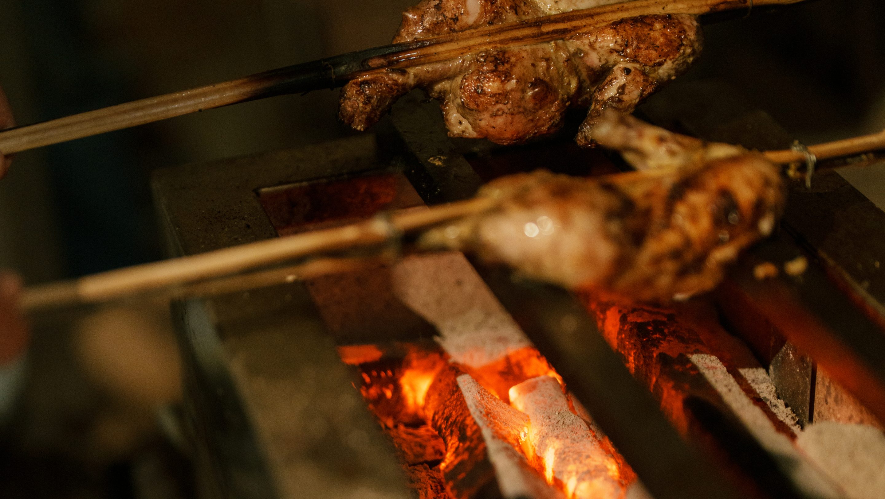 Chicken skewers cooking over glowing charcoal